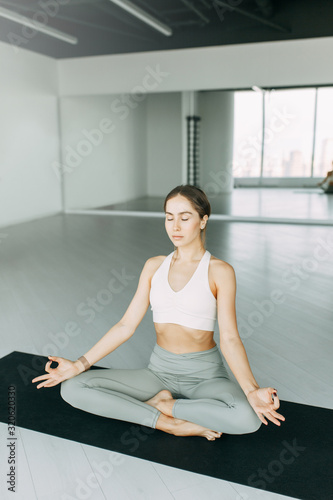  Exercises for self-control in yoga. Bright gym. Relaxed posture during meditation. The girl is sitting on the Mat, relax.
