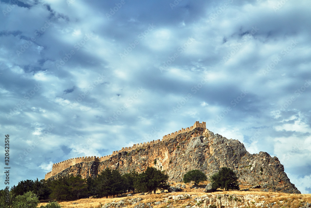 walls of a medieval fortress on top of a rocky hill in Lindos.