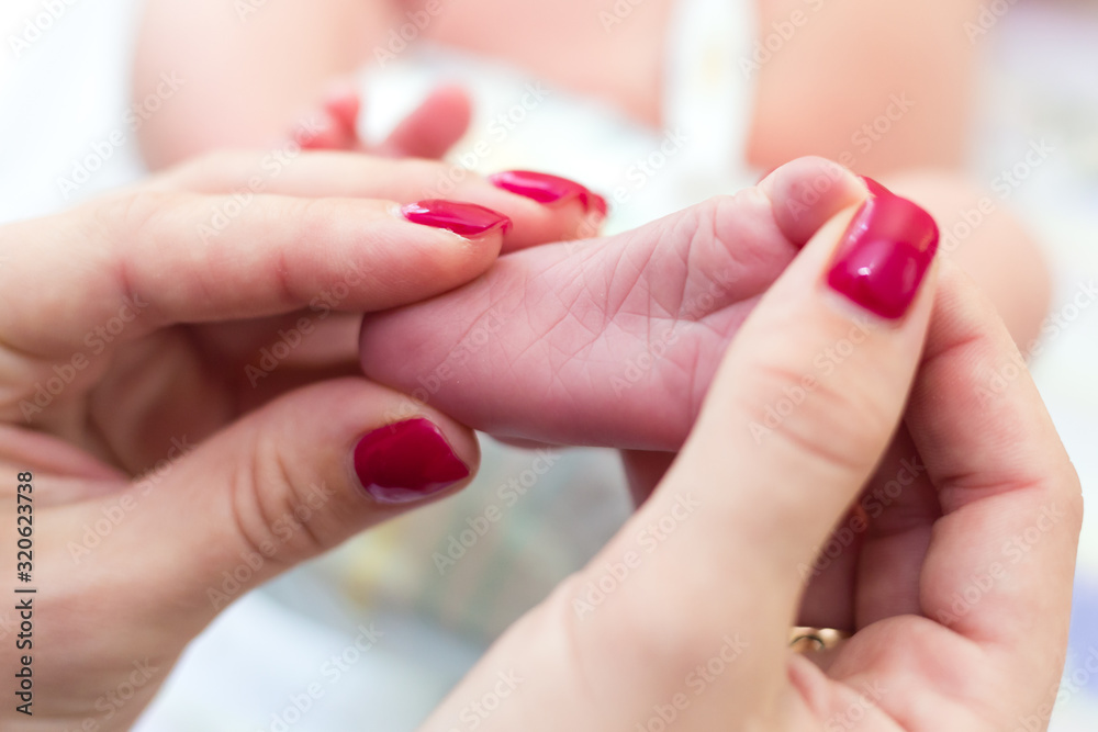 Newborn's legs are small in the hands of parents