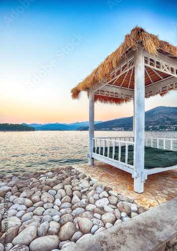 Fototapeta Naklejka Na Ścianę i Meble -  Thatched canopies and awnings on the beach Copacabana at sunset in Dubrovnik