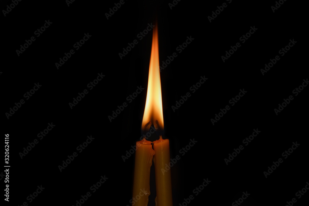 Two candles with merged into one flame on a black background Two candles with merged into one flame on a black background