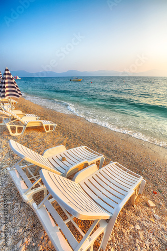 Sun loungers and beach umbrellas at sunset on the beach of Gradac in Makarska riviera