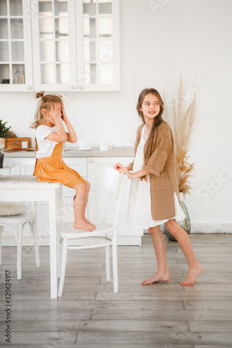 Two sisters play in a bright, stylish kitchen. Beautiful interior.