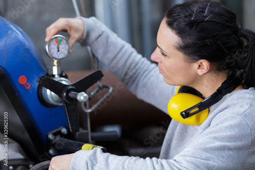 female engineer rotating valve on tank inside factory