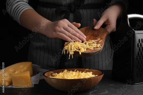 Woman with grated cheese at table, closeup