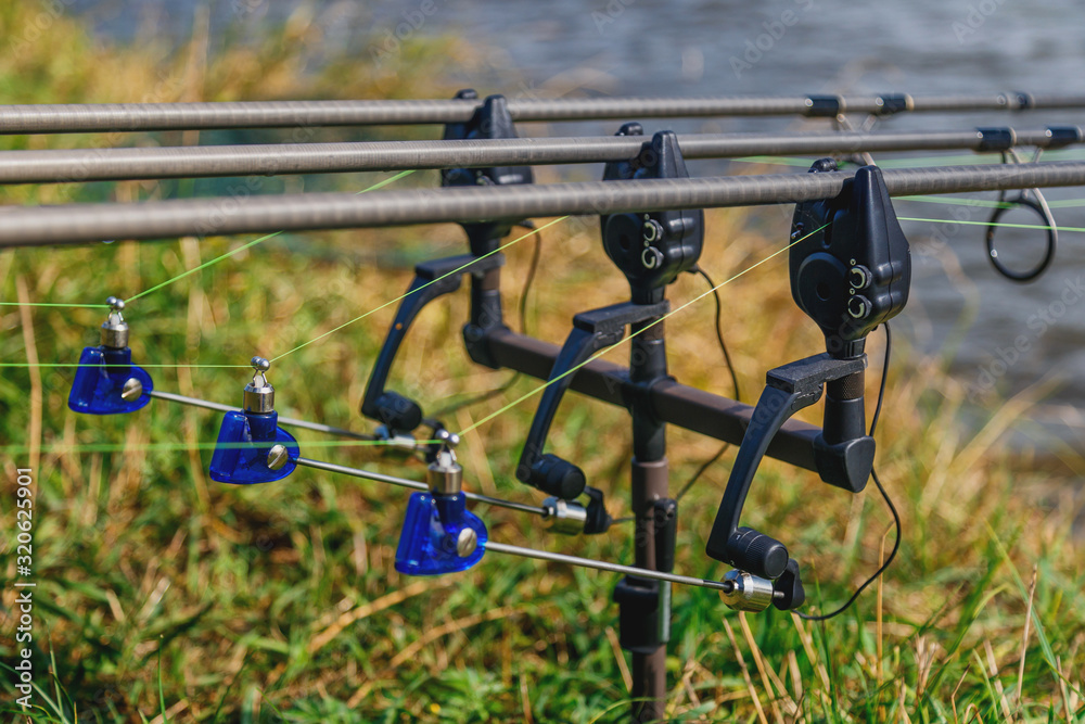Fishing adventures, carp fishing. Carp fishing rods set up on holder with bite alarms and illuminated indicators . Professional fishing equipment Fishing adventures, carp fishing. Carp fishing rods set up on holder with bite alarms and illuminated indicators . Professional fishing equipment