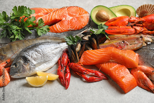 Fresh fish and different seafood on light grey table, closeup