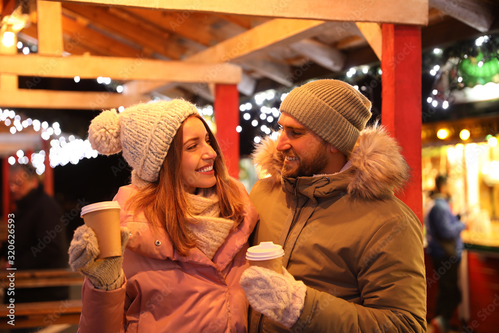 Happy couple with drinks at Christmas fair