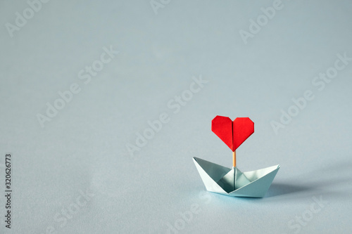 Valentine's day greeting card. Origami boat with heart flag on glitter blue background Romantic, Valentines day concept with space for text. photo