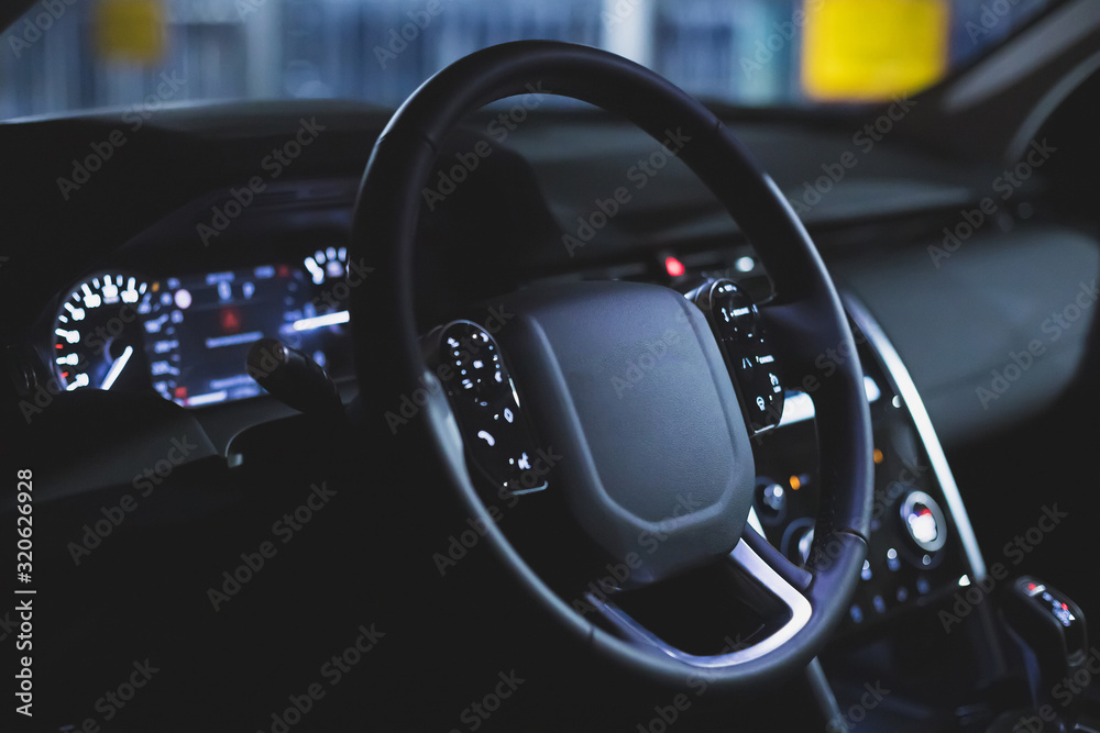 black leather multi-function steering wheel in the interior of a premium SUV.  car dashboard.  control buttons. matte toned