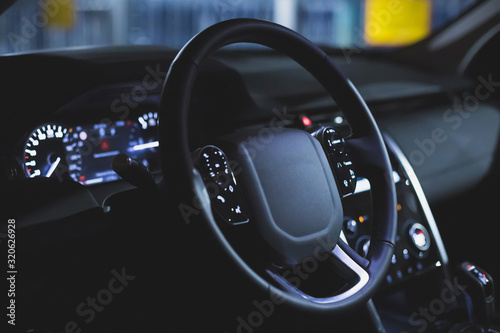 black leather multi-function steering wheel in the interior of a premium SUV. car dashboard. control buttons. matte toned