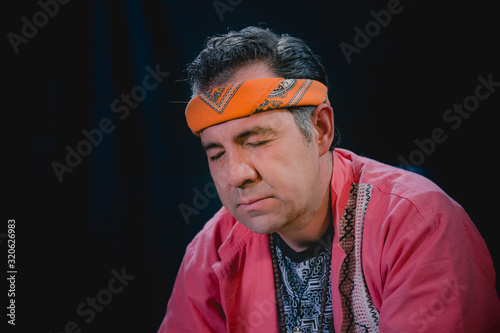 Shaman man, sorcerer, giving thanks duringPre-Hispanic ritual in Healing and cleaning with medicinal plants in Mexico, with black background photo