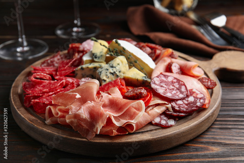 Tasty prosciutto with other delicacies served on wooden table