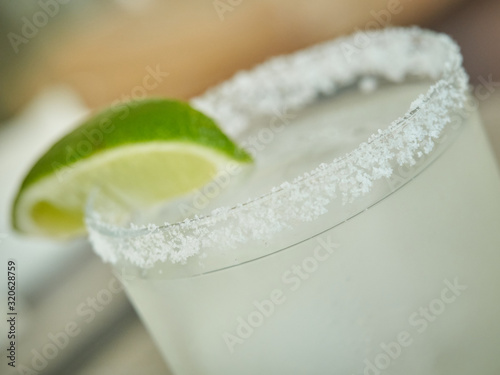 Fotografija Glass rim garnished with salt and slice of lime , margarita drink light green ,