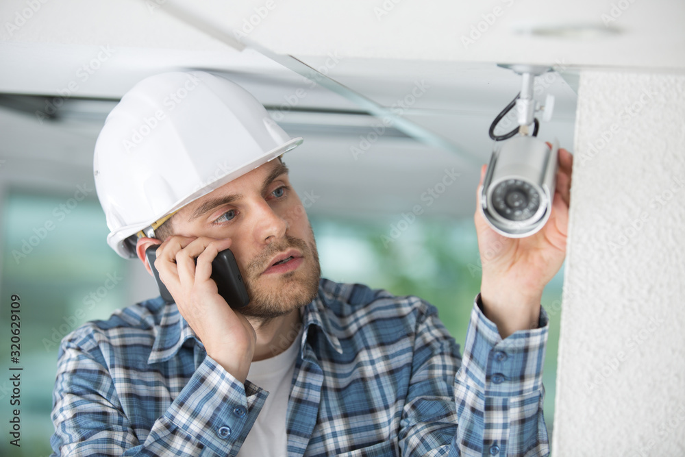 contractor talking on telephone by cctv camera contractor talking on telephone by cctv camera