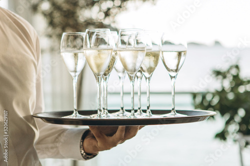 Fotografia The waiter is holding a tray with glasses of champagne or white sparkling wine