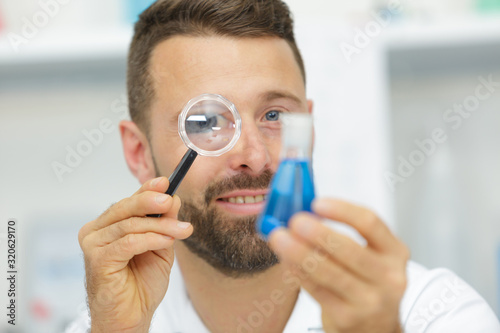 happy man looking at mite through magnifier