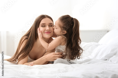 Happy mother with little daughter in bedroom