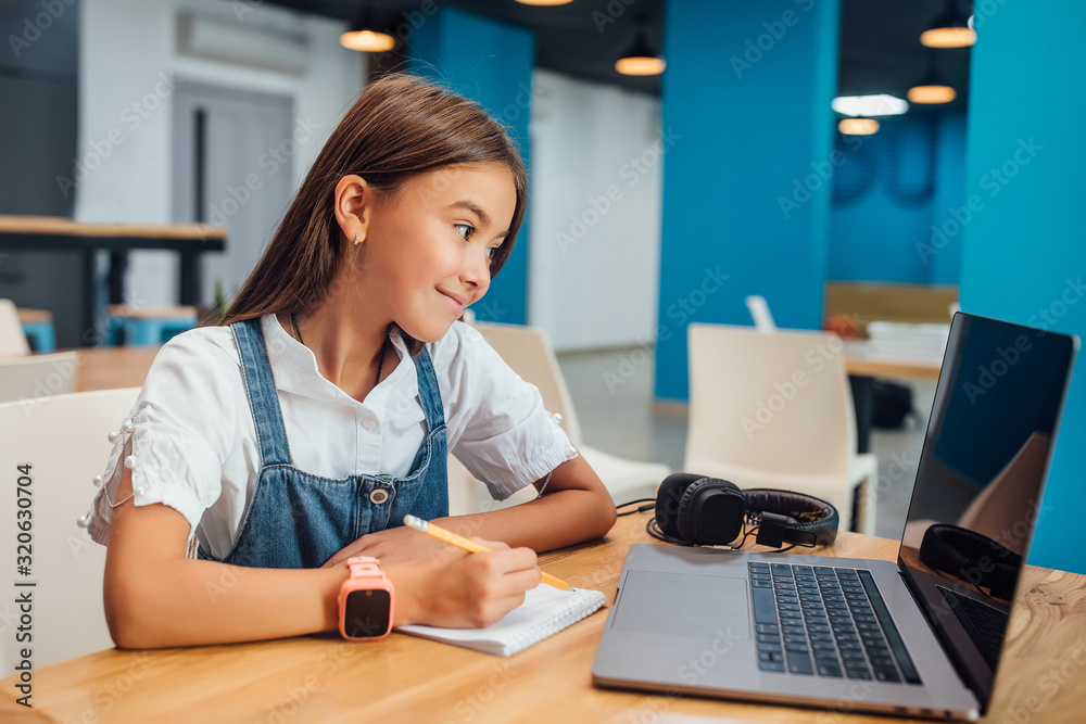Pretty girl using a laptop computer at modern school. Pretty girl using a laptop computer at modern school.
