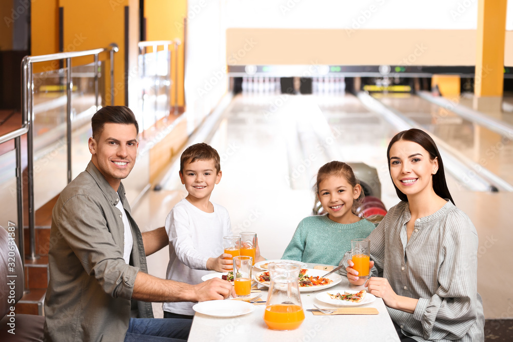 Happy family with pizza and drinks in bowling club