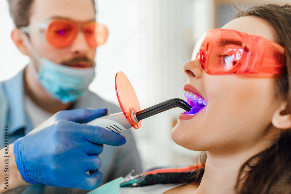 © Тарас Нагирняк - Medicine, dentistry and healthcare concept, dentist male using dental curing UV lamp on teeth of patient. © Тарас Нагирняк - Medicine, dentistry and healthcare concept, dentist male using dental curing UV lamp on teeth of patient.