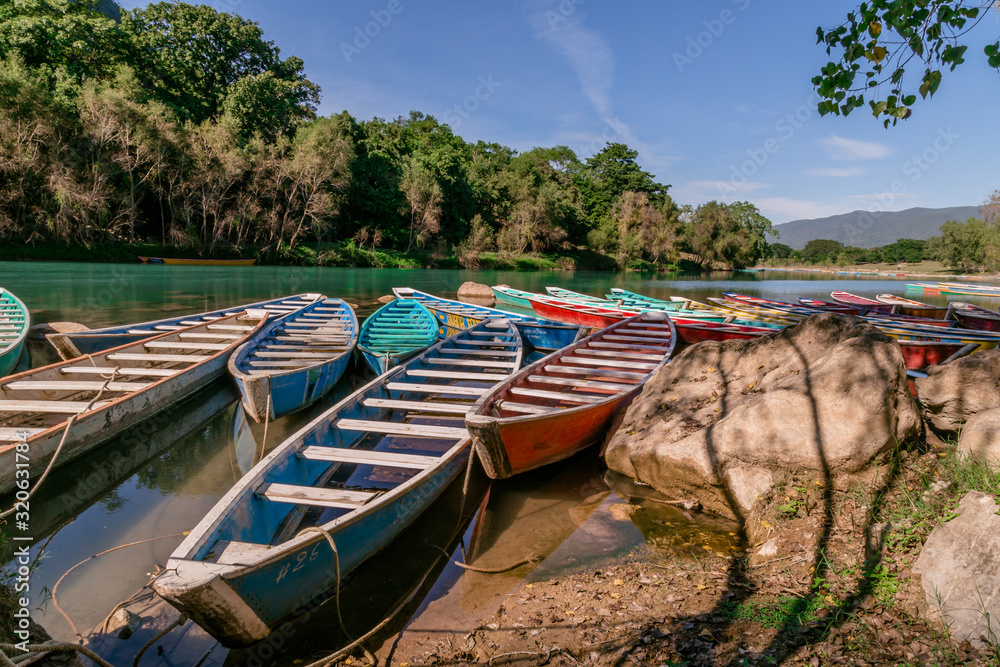 Obraz premium TAMUL, SAN LUIS POTOSI MEXICO - January 6, 2020:Colorful canoes on the Tamul river in Huasteca, these canoes will be used for the river tour and until you reach the waterfall