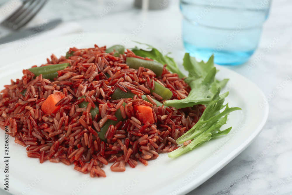 Tasty brown rice with vegetables on white marble table, closeup