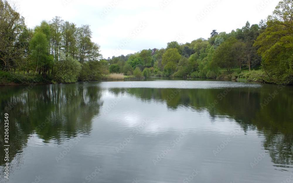 A lake surrounded by trees reflecting in the water A lake surrounded by trees reflecting in the water
