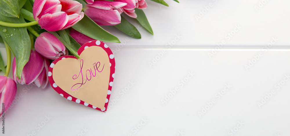 Bouquet of pink tulips with heart shaped card for Valentine's day.