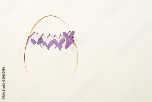 paper yellow egg split into two halves with paper purple hares for Easter