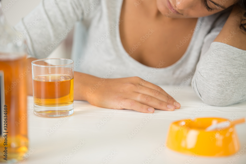 bottle with alcohol on table and drunk woman on background bottle with alcohol on table and drunk woman on background