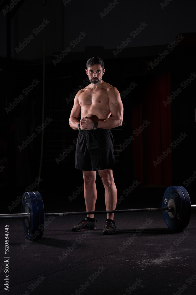 Strong man with barbell with weights in his hands doing strength exercises in the gym with magnesium in his hands. Young athlete practicing multidisciplinary training Strong man with barbell with weights in his hands doing strength exercises in the gym with magnesium in his hands. Young athlete practicing multidisciplinary training