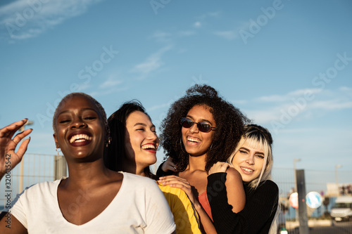 Confident young multiethnic female friends enjoying pastime in street