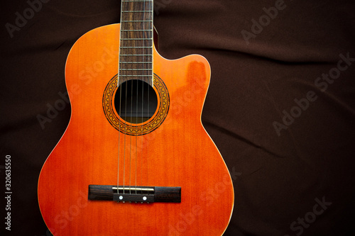Six-string acoustic guitar on a dark brown background. Classical Spanish guitar. Musical instrument. Place for text.