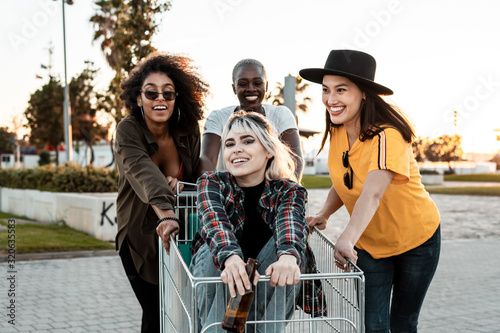 Multiracial group of young women standing around shopping cart on road photo