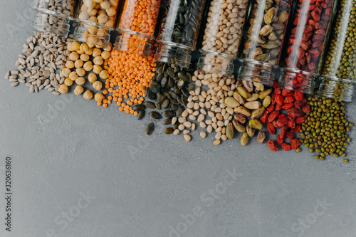 Healthy products in glass jars. Organic grains in containers on grey background. Blank space at bottom for your promotional text. Vegetarian food photo