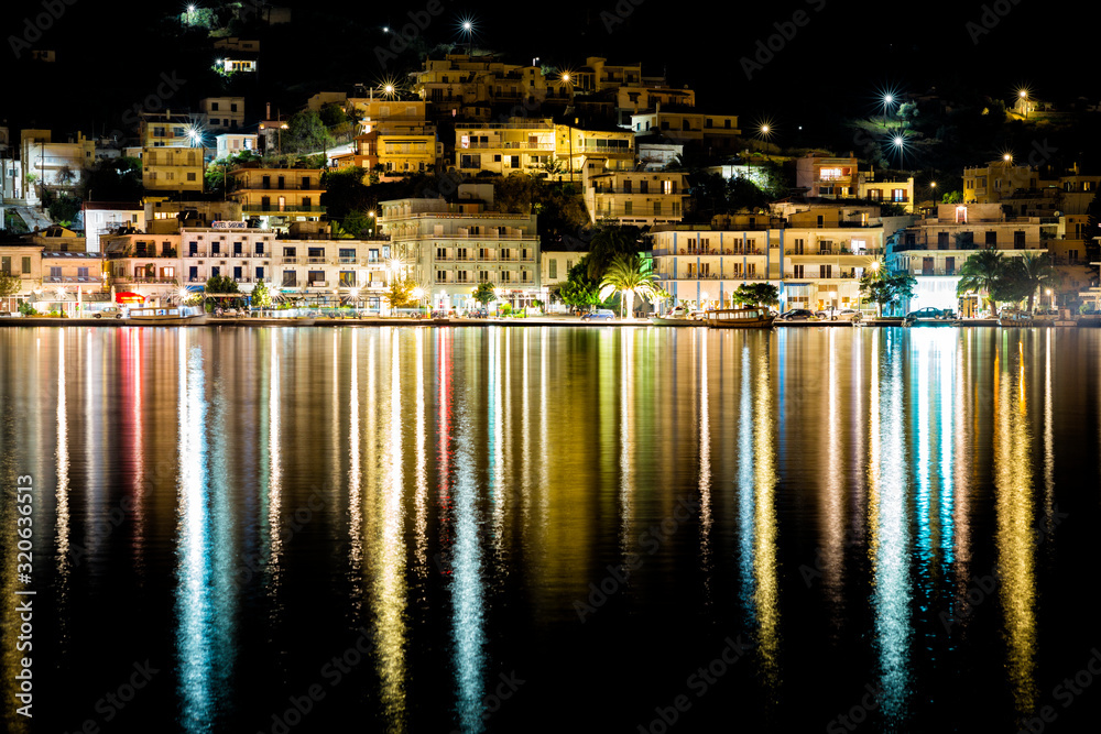 Poros, Greece at night hillside waterfront city with lights reflecting in the water