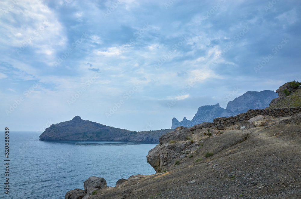 A tourist route along a trail in the mountains of the southern coast of Crimea, a beautiful view of the Black Sea and rocks. Cloudy sky, Republic of Crimea