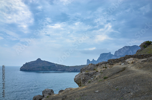 Obraz na płótnie A tourist route along a trail in the mountains of the southern coast of Crimea, a beautiful view of the Black Sea and rocks. Cloudy sky, Republic of Crimea w salonie