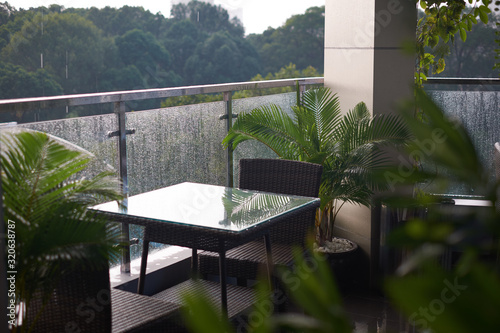Photo of the table and two chairs on a cozy balcony with view on the rainy nature