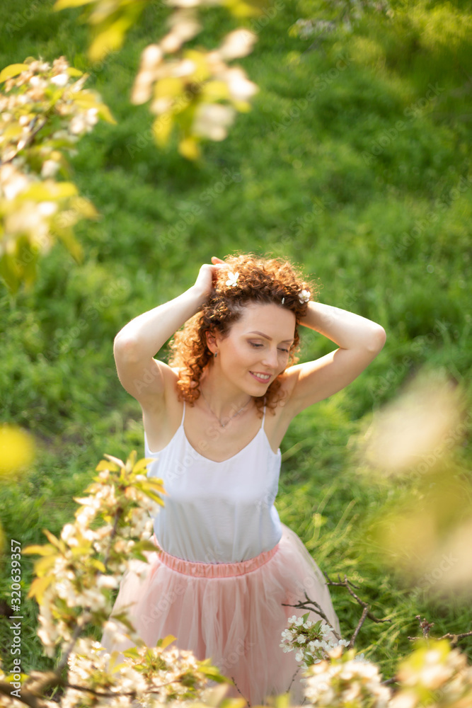 Young attractive girl walks in spring green park enjoying flowering nature Young attractive girl walks in spring green park enjoying flowering nature