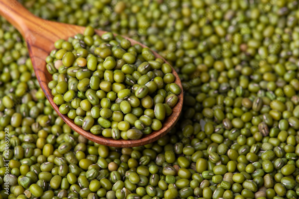 Scattered mung bean. Eco spoon. Mung bean, green moong in a wooden spoon, on black metallic vintage background. Copy space. Black background. Scattered mung bean. Eco spoon. Mung bean, green moong in a wooden spoon, on black metallic vintage background. Copy space. Black background.