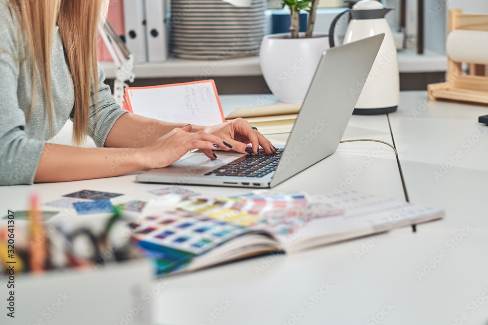 Fototapeta premium Woman with nice manicure is working on computer at creative studio.