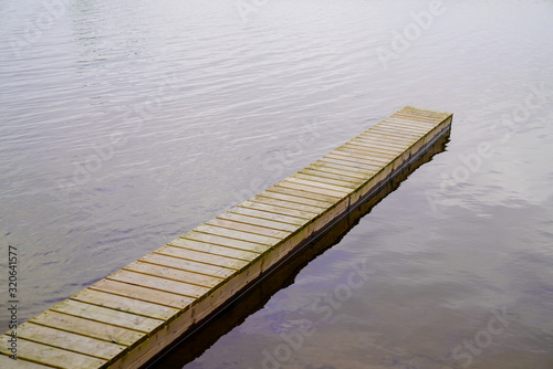 Narrow wooden pontoon over lake water photo