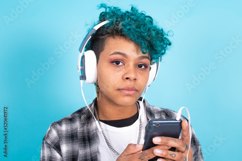 african american girl or woman with phone and headphones isolated on blue background