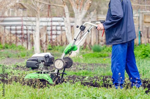 A man cultivates the land with a cultivator in a spring garden