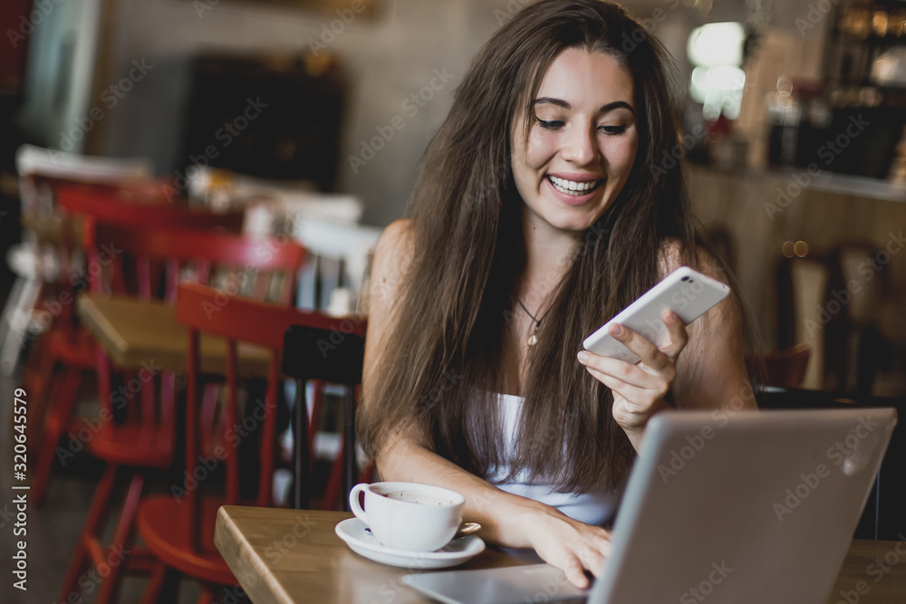 Business woman using phone, working on a laptop and drinking coffee in a cafe. Business woman using phone, working on a laptop and drinking coffee in a cafe.