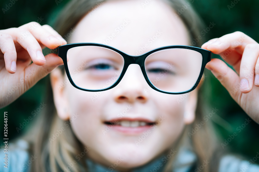 Closeup portrait of little girl with myopia correction glasses. Girl is