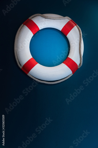 Bright Life Buoy in dark background. Personal life support flotation safety device for swimmers, passengers or marine personnel working in area exposed to water. Drowning Protection Equipment concept.