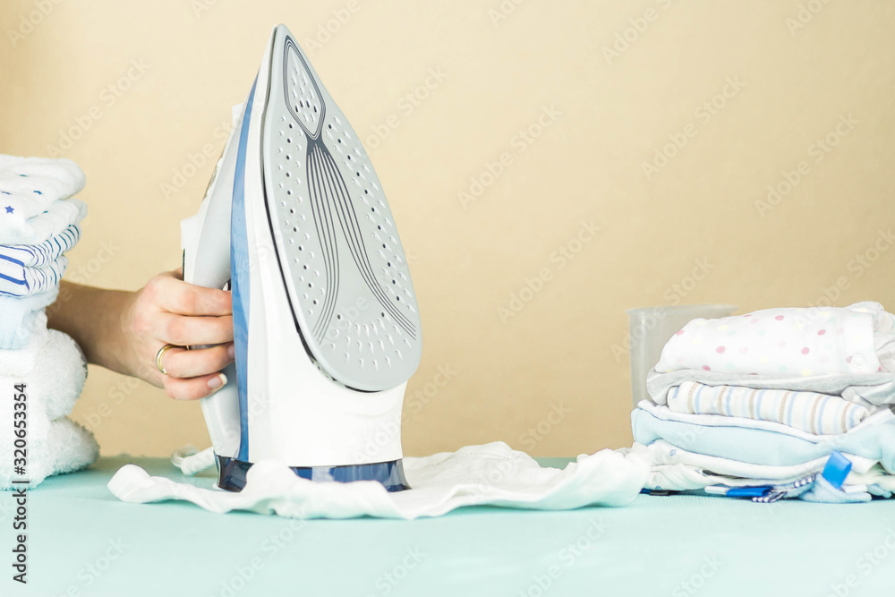 Woman hand pressing, ironing. Ironing newborn baby clothes with an